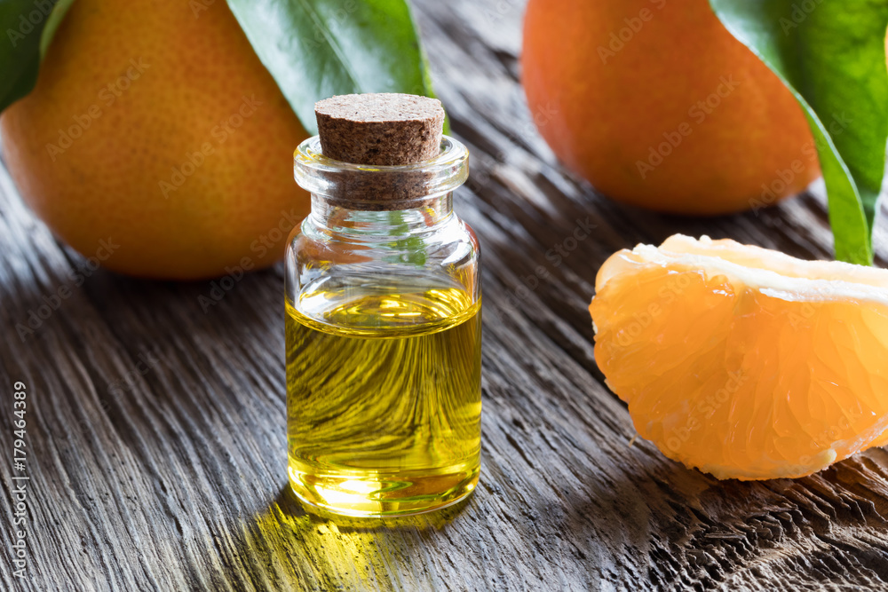 A bottle of tangerine essential oil on a wooden background A bottle of tangerine essential oil on a wooden background