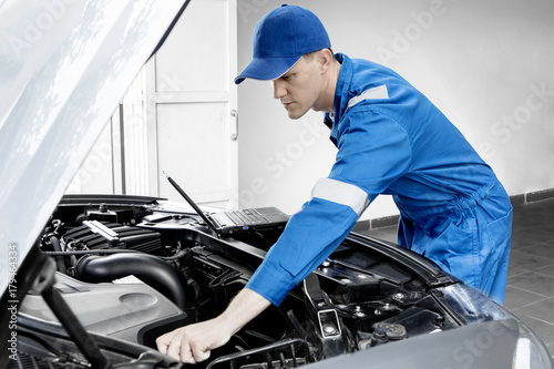 American mechanic checking car with a laptop © Creativa Images