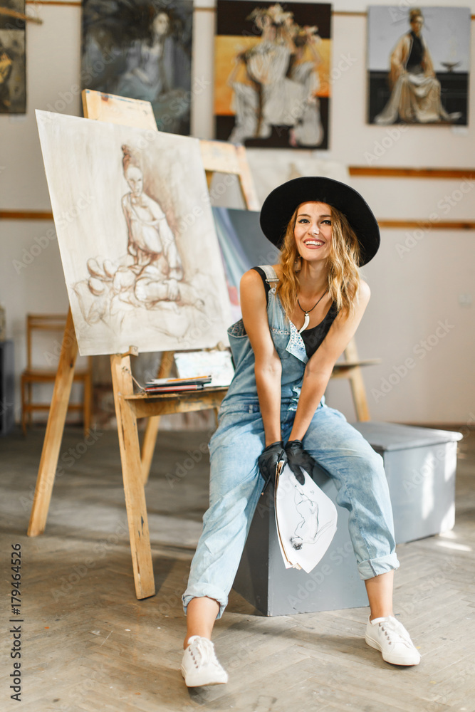 Obraz premium Female artist wears black hat posing near picture indoor the studio