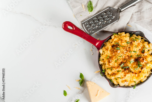 Mac and cheese, american style macaroni pasta with cheesy sauce and crunchy breadcrumbs topping, in portioned pan, white marble table, copy space top view photo