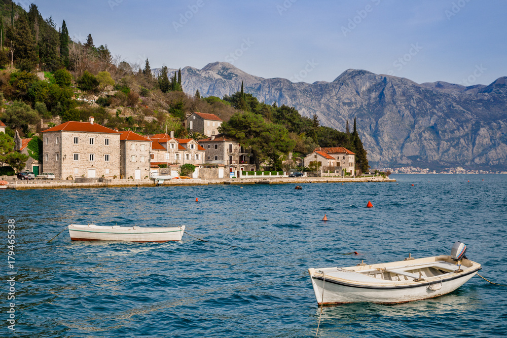 Fototapeta premium white boat in bay next to houses with red roof background mountain in sunny day