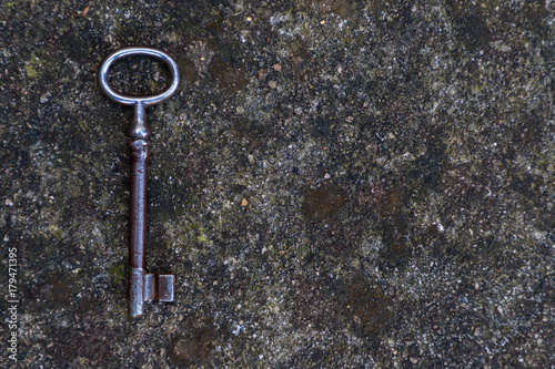 Old dirty vintage metal key on stone background © pjosto