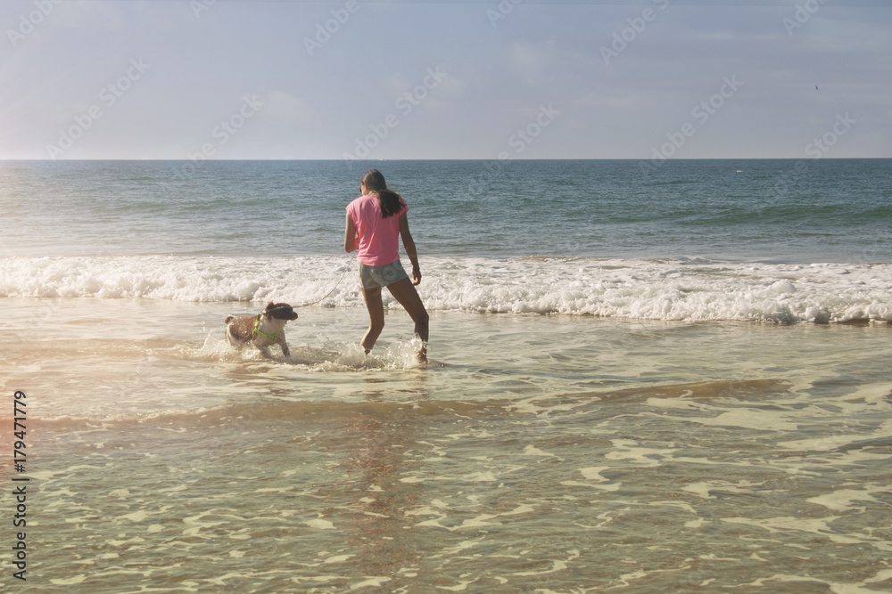 girl playing with dog on the sea shore