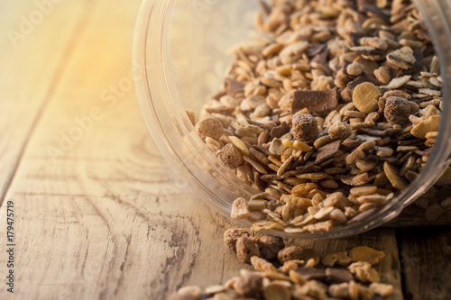 Close-up of muesli spilling from bowl on the wooden table photo