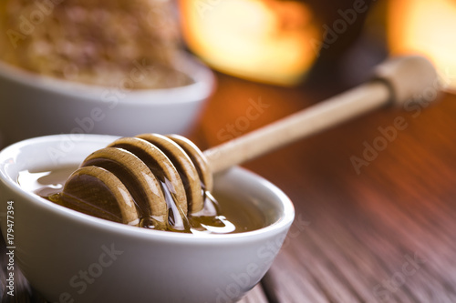 Honey in jar with honey dipper on wooden background 