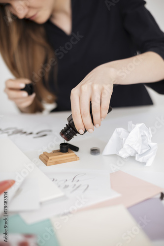 Close up of young woman hand pouring ink into ink tank isolated