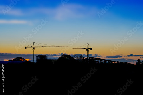 Skyline and silhouette of crane in building construction site on evening background © lamyai