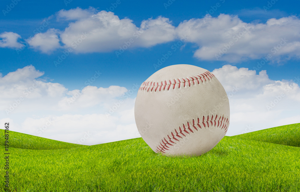 old white baseball on grass and blue sky background.