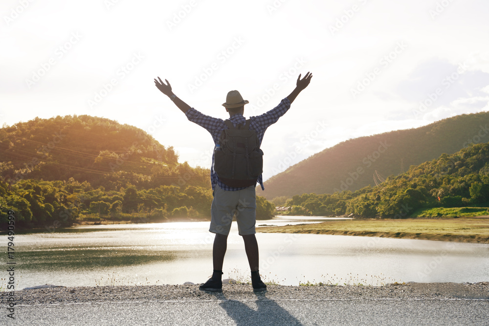 Young Asian tourist man with backpack traveling and enjoying on the river bank Young Asian tourist man with backpack traveling and enjoying on the river bank