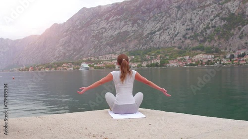 Beautiful yoga with amazing view of sea on background, pretty healthy woman with perfect body stand in one of yoga pose photo