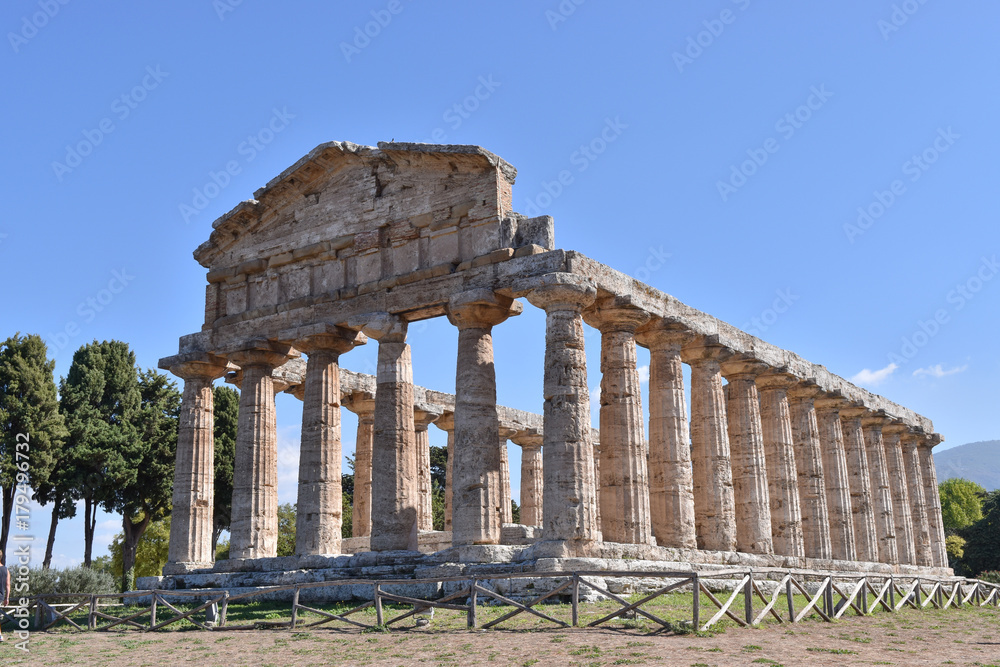 Monument of antiquity/Well-preserved antique temple against the background of a bright blue sky