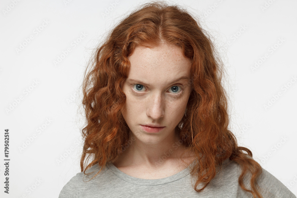 Closeup headshot of young beautiful redhead European female isolated on white background raising one eyebrow in expression of mistrust and doubt as if questioning reality of actual state of things Closeup headshot of young beautiful redhead European female isolated on white background raising one eyebrow in expression of mistrust and doubt as if questioning reality of actual state of things