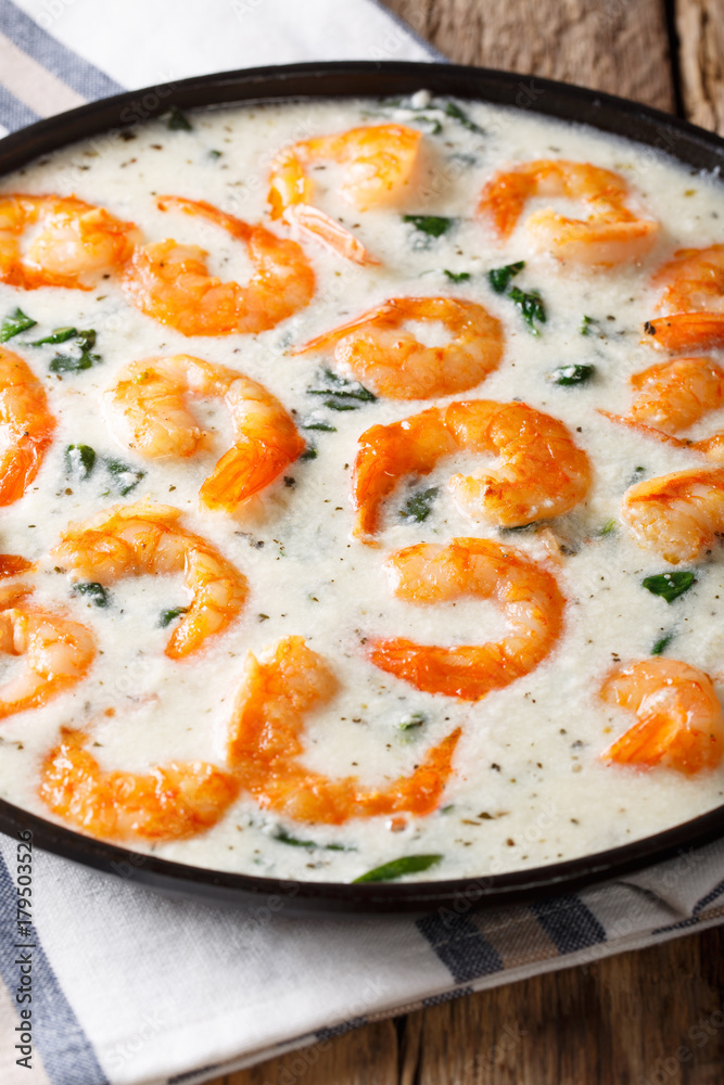 Spicy prawns with spinach in creamy cheese sauce close-up on a plate. vertical