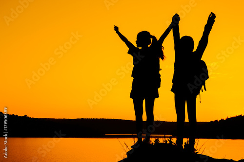 Silhouette two girls join hands to celebrate the success of the trip.