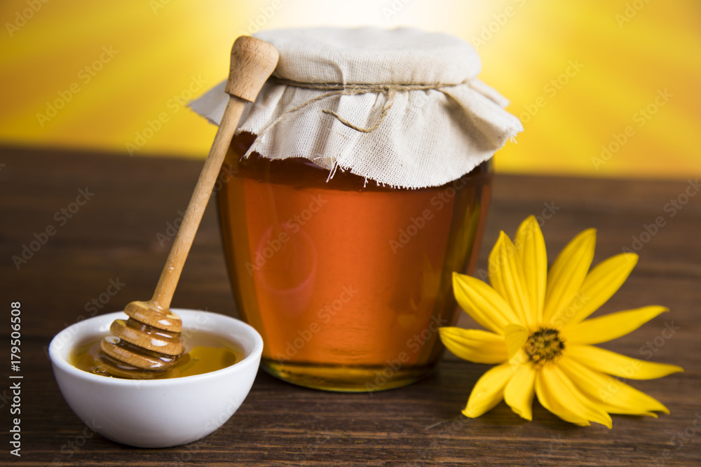 Honey in jar with honey dipper on wooden background Honey in jar with honey dipper on wooden background