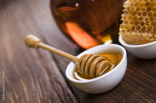 Honey in jar with honey dipper on wooden background 