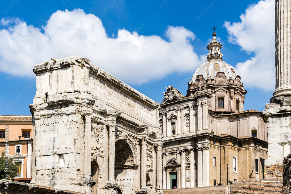 Arch of Septimus Severus, ancient Roman Forum, Rome, Italy. View of the ruins of antique Arch, baroque church in background.