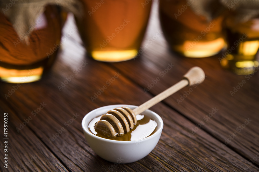 Honey and wooden stick are on a table Honey and wooden stick are on a table