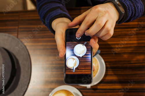 Top view. Woman doing the photo of Two white cups of coffee on the wooden table.