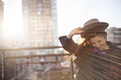 Outdoor portrait. Young stylish pretty woman with hat in hand posing in the big city streets. 