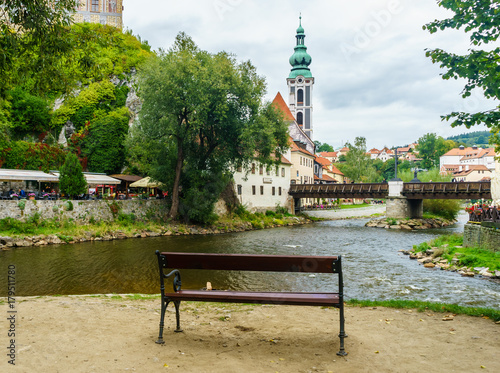 A bench on a small island on the Vltava River in Cesky Krumlov in the Czech Republic. Pedestrian bridge across Vltava