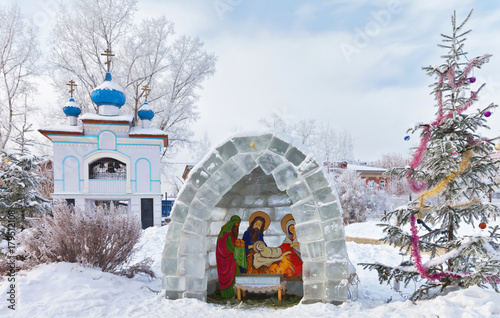 Irkutsk in the winter. Christmas vertep composition in the courtyard of the Assumption Church against the backdrop of bell-ringed with blue domes on a frosty January day photo