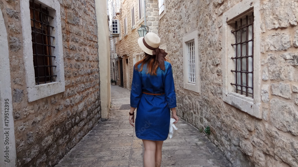 Девушка в шляпе путешествует а Черногории. Старый город. Будва