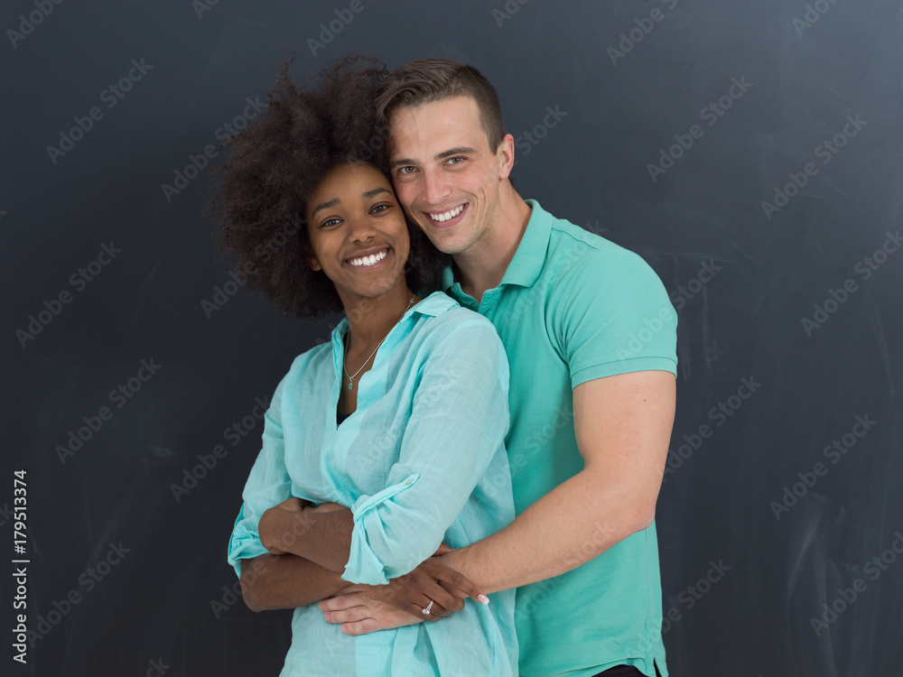 multiethnic couple in front of gray chalkboard multiethnic couple in front of gray chalkboard