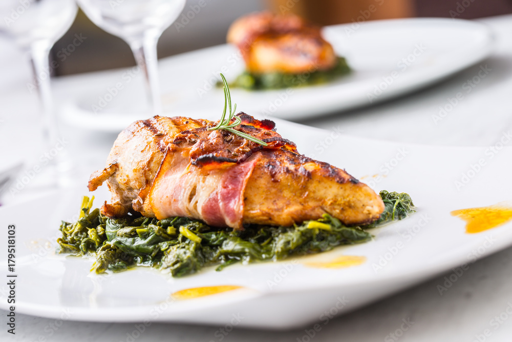 Chicken grill breast. Chicken roasted breast with bacon and spinach on white plate. Culinary food in hotel pub or restaurant Chicken grill breast. Chicken roasted breast with bacon and spinach on white plate. Culinary food in hotel pub or restaurant