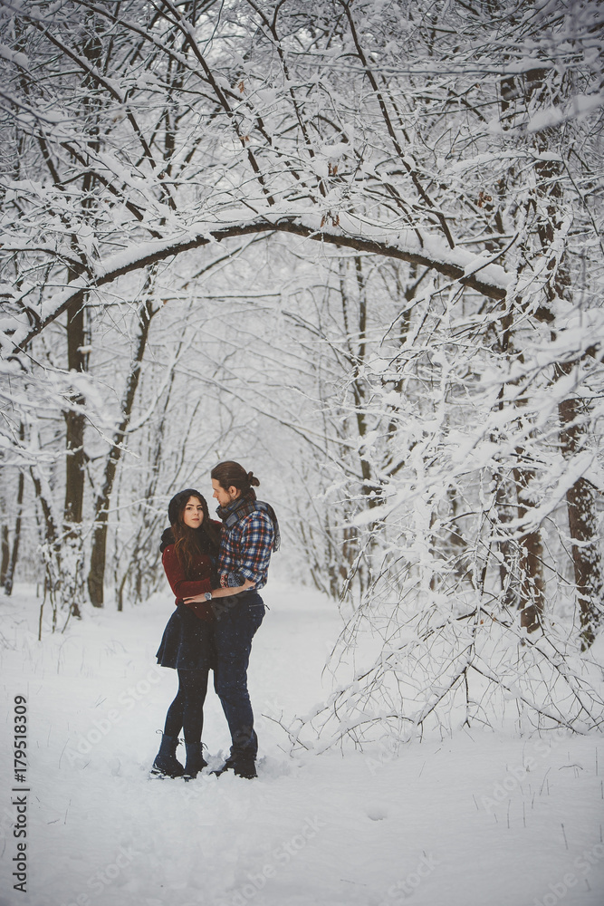 Happy loving couple walking in snowy winter forest