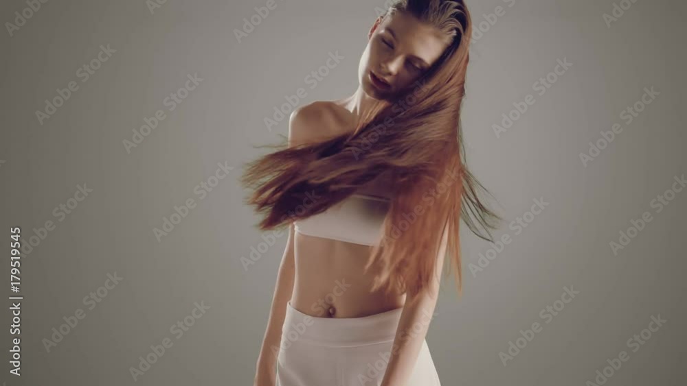 Beautiful fashion model young Caucasian girl sensual hair movement over a minimal grey background in slow motion prores .