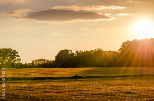 Sunset over a field path with a lamp.