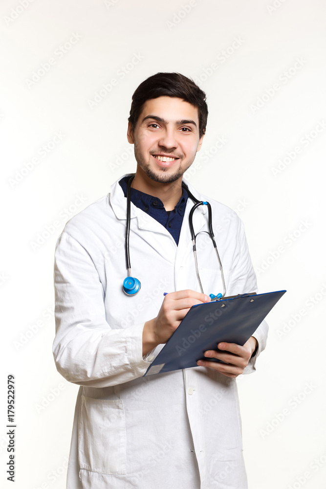 beautiful young doctor in a dressing gown with a stethoscope on a white background in the studio, records a medical history, beautiful young doctor in a dressing gown with a stethoscope on a white background in the studio, records a medical history,