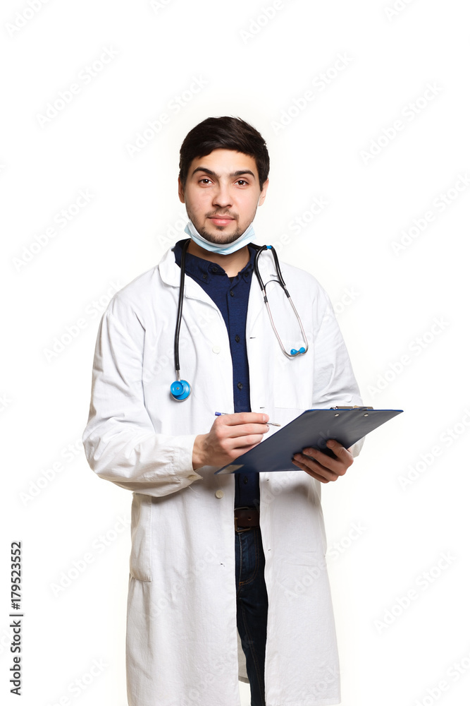beautiful young doctor in a dressing gown with a stethoscope on a white background in the studio, records a medical history beautiful young doctor in a dressing gown with a stethoscope on a white background in the studio, records a medical history