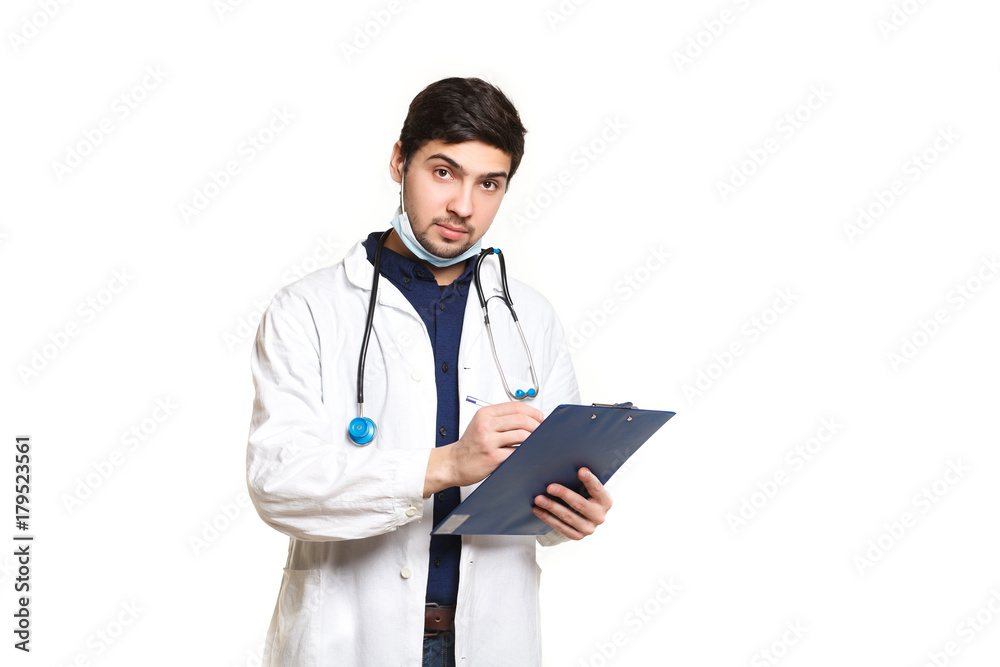 beautiful young doctor in a dressing gown with a stethoscope on a white background in the studio,with the ass, records a medical history beautiful young doctor in a dressing gown with a stethoscope on a white background in the studio,with the ass, records a medical history