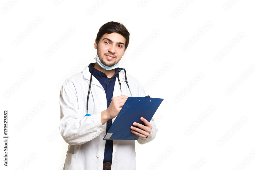 beautiful young doctor in a dressing gown with a stethoscope on a white background in the studio,with the ass, records a medical history beautiful young doctor in a dressing gown with a stethoscope on a white background in the studio,with the ass, records a medical history