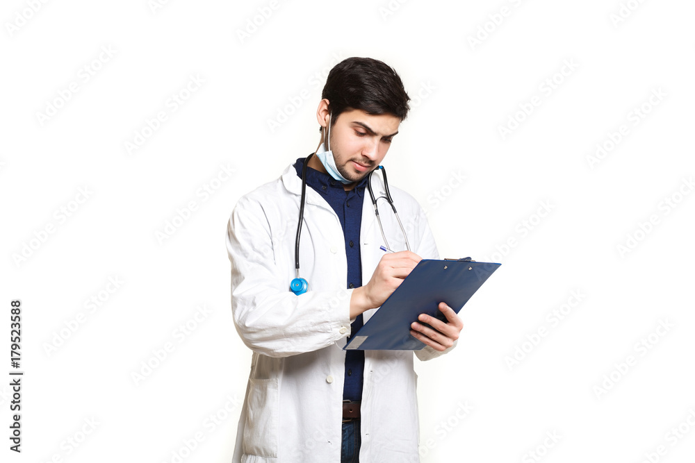 beautiful young doctor in a dressing gown with a stethoscope on a white background in the studio,with the ass, records a medical history beautiful young doctor in a dressing gown with a stethoscope on a white background in the studio,with the ass, records a medical history
