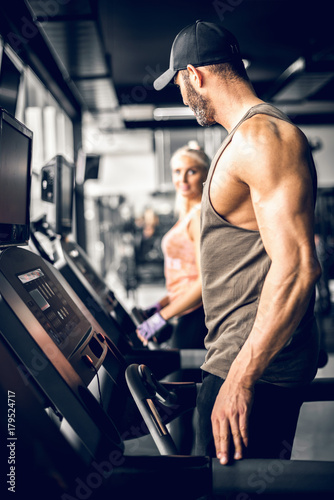 Attractive man running on treadmill and looking at girl