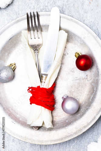 Christmas table place setting. Holidays background. Silver plate, knife and fork with christmas decorations. Top view.