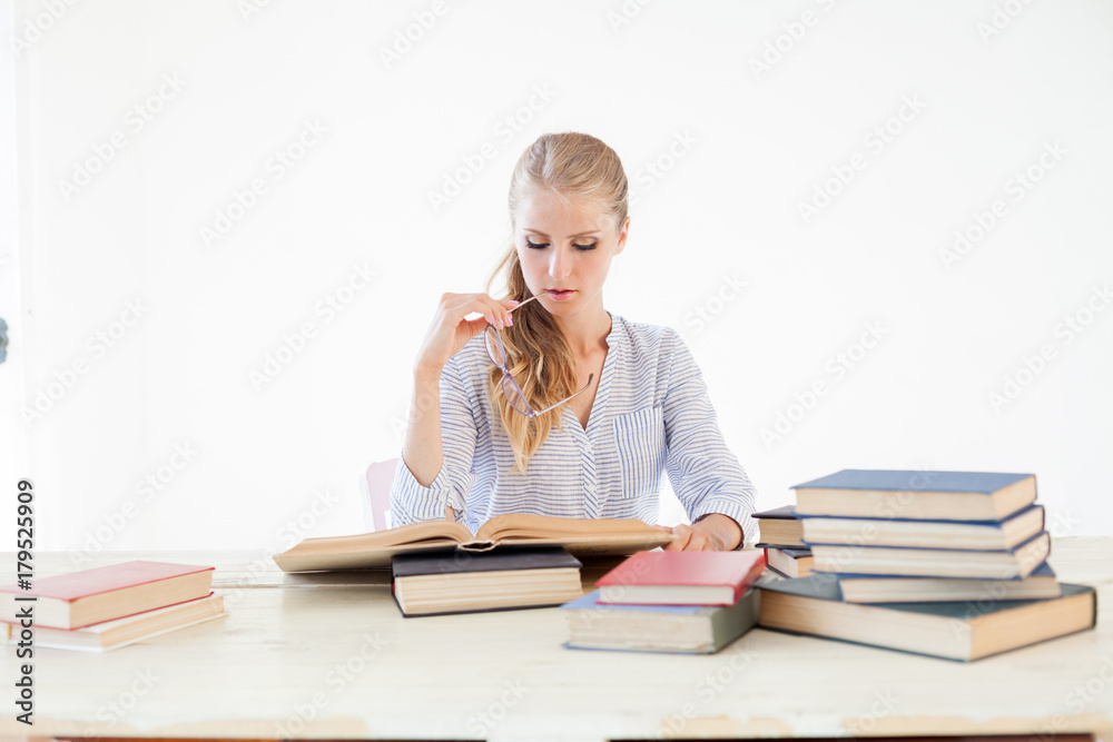 female teacher sitting at a table of many books Office female teacher sitting at a table of many books Office