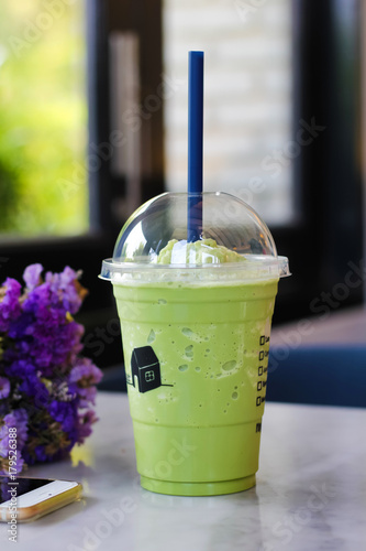 Blended green tea and blue straw in a plastic glass