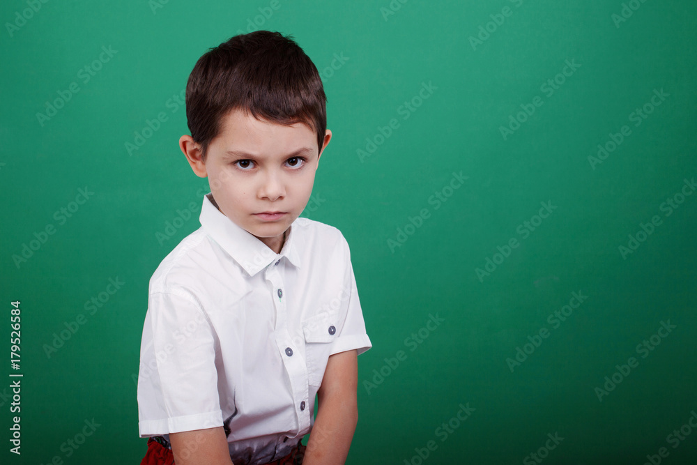 Boy in white shirt on green background, close-up portrait