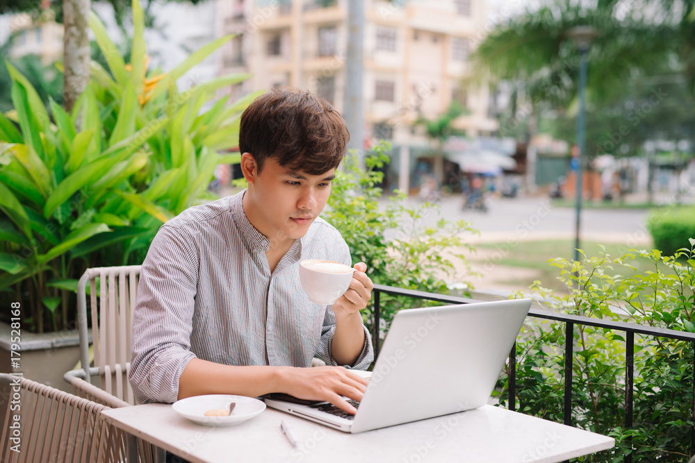 Young male freelancer working with laptop computer in comfortable coffee shop
