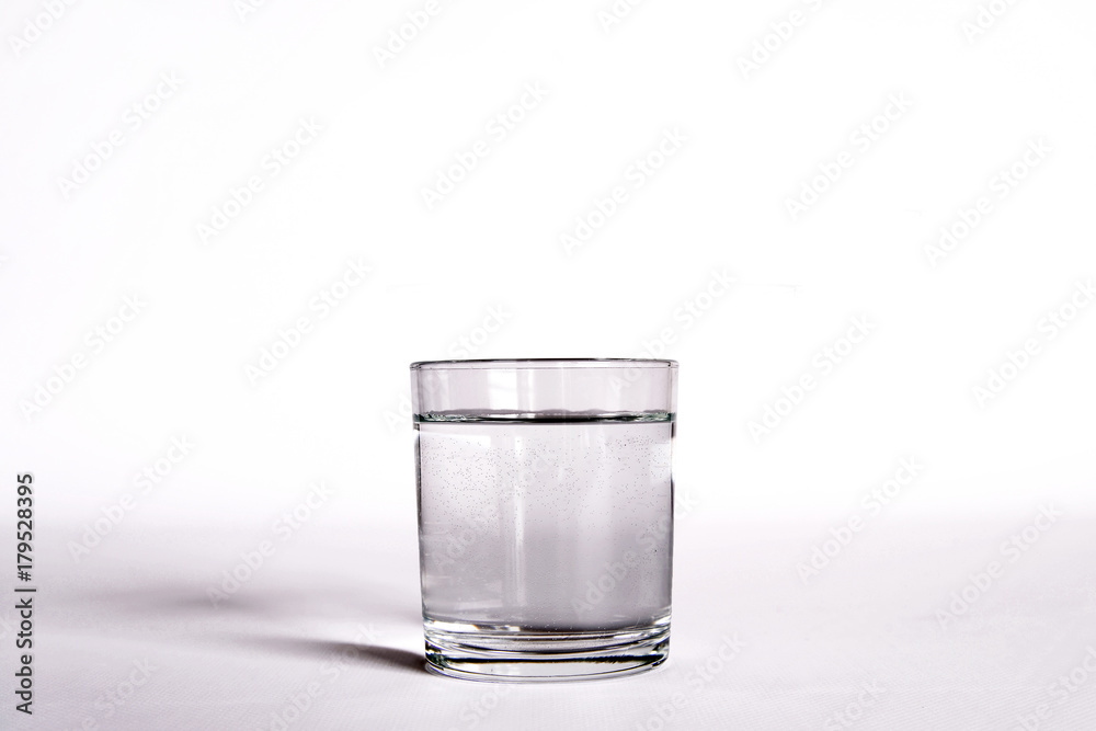un bicchiere trasparente pieno di acqua. vicino una bottiglia di acqua minerale. composizione con bottiglie di acqua minerale un bicchiere trasparente pieno di acqua. vicino una bottiglia di acqua minerale. composizione con bottiglie di acqua minerale