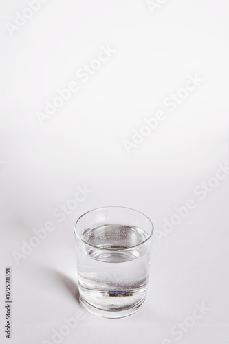 un bicchiere trasparente pieno di acqua. vicino una bottiglia di acqua minerale. composizione con bottiglie di acqua minerale