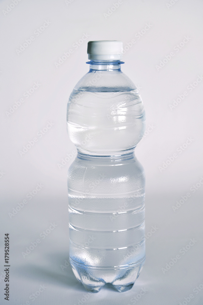 un bicchiere trasparente pieno di acqua. vicino una bottiglia di acqua minerale. composizione con bottiglie di acqua minerale un bicchiere trasparente pieno di acqua. vicino una bottiglia di acqua minerale. composizione con bottiglie di acqua minerale