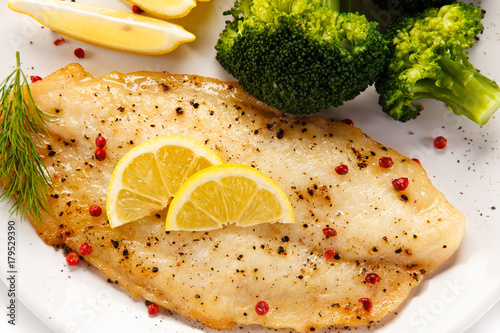 Konstfotografi Fried fish fillet with broccoli on white background