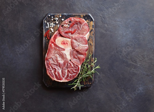 Meat.Raw veal cut with herbs and spice ready to cook on rustic wooden cutting board. Dark background