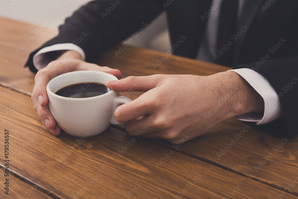 Businessman holding cup of coffee, close up