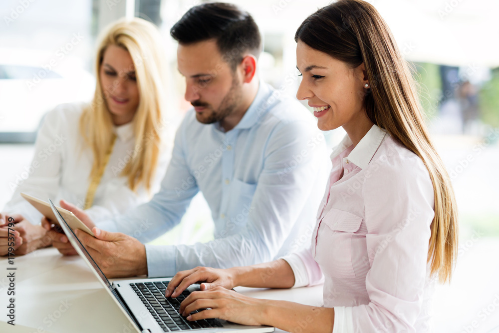 Three young smiling colleagues working together on laptop Three young smiling colleagues working together on laptop